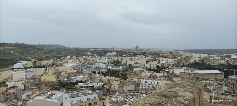 Vue panoramique de Gozo, montrant un large paysage urbain avec, au loin, la campagne maltaise.