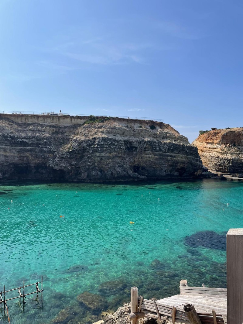 Eaux turquoise au pied des falaises près du Popeye Village, avec un petit ponton en bois au premier plan.