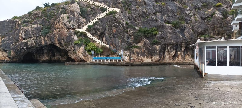 Crique de Xlendi, à Gozo où l'on voit l'entrée d'une grotte et un escalier en zigzag qui grimpe le long de la roche.