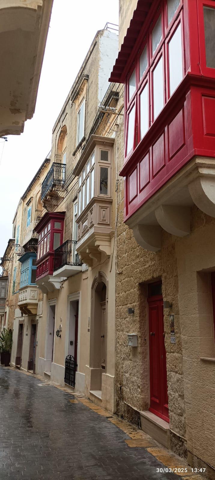 Maison traditionnelle avec un grand balcon fermé rouge.
