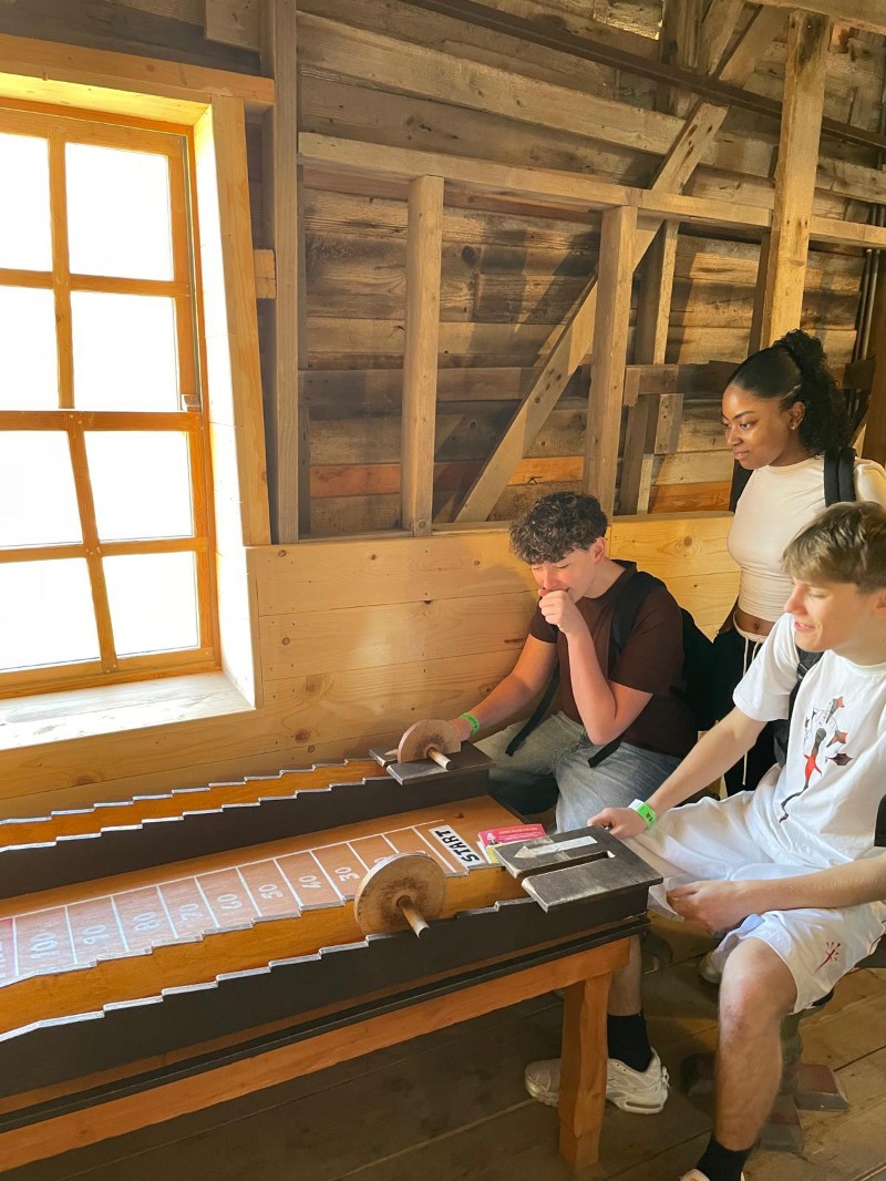 Trois élèves concentrés autour d'un jeu antique gravé sur pierre.