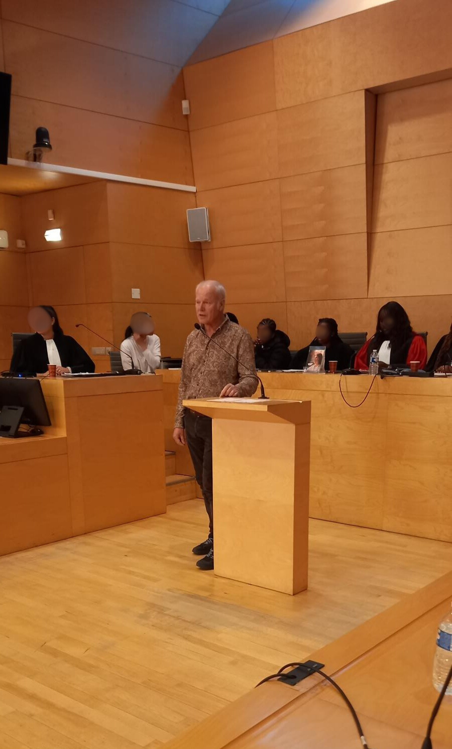 Photo de la cour reconstituée, avec les élèves dans les rôles de magistrats, accusée et l'auteur au pupitre s'adressant à la salle.